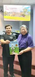 Pastor Hoa teaching xavier gifting Xavier a book about the 30 years of Grace Church